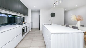A modern kitchen with white cabinetry, a built-in stove, and a large island with a sink.
