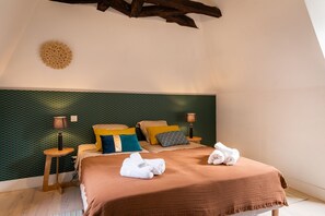 A bedroom with a green patterned headboard, a wooden bed frame, two bedside tables with lamps, and a brown bedspread. - Le jardin de la Paix - Historic centre (Sarlat-la-Canéda)