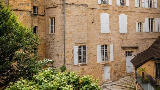 Un bâtiment historique en pierre, doté de nombreuses fenêtres et d’un toit à forte pente.