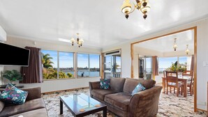 A spacious living room with a large window, a sofa, a coffee table, and a dining area with a view of the city.