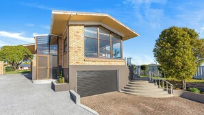 Une maison moderne à deux étages, dotée d ’un garage, d’une allée couverte et d’un escalier menant à l’entrée.