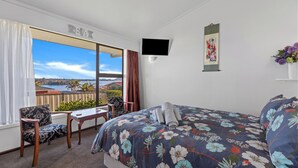 Une chambre d’hôtel avec un grand lit, un bureau, une chaise, une télévision et une vue sur la mer.