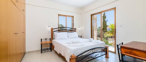 A bedroom with a bed, a wooden table, and a chair.