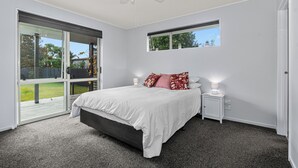 A bedroom with a large bed, a ceiling fan, a window, and a view of the outdoors.