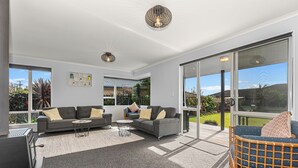 A modern living room with a grey sofa, a small round table, and a wicker chair.