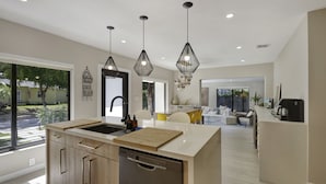 A modern kitchen with a central island, pendant lighting, and a view of the outdoor area.