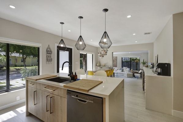A modern kitchen with a central island, pendant lighting, and a view of the outdoor area.