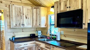 Eine Holz-Küche mit Mikrowelle, Spüle und Schränken.