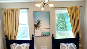 A bedroom with two beds, a nightstand, a lamp, and a ceiling light fixture.