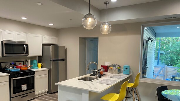 A modern kitchen with stainless steel appliances, a marble countertop island, and a view of the backyard.