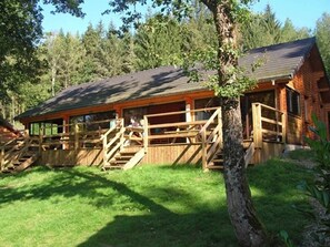 Eine rustikale Holzhütte mit einer Holzterrasse und einer Treppe, die zu einem überdachten Bereich führt.