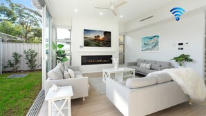 A modern living room with a fireplace, two sofas, a coffee table, and a ceiling fan.