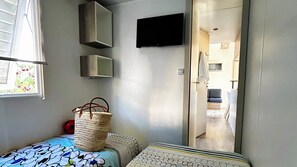 A bedroom with a bed, a woven basket, and a TV mounted on the wall.