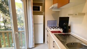A compact kitchen with a gas stove, a microwave, and a refrigerator.