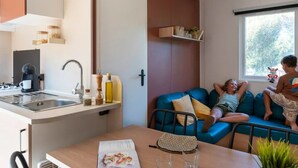 A compact living space with a kitchenette, a dining area, and a window with a view of greenery.