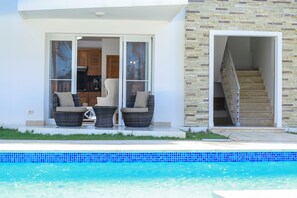 Ein modernes Haus mit Pool, zwei Korbstühlen und einer Treppe zu einer oberen Ebene.