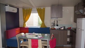 A compact kitchen with a dining area, featuring a built-in bench, a small table, and a refrigerator.