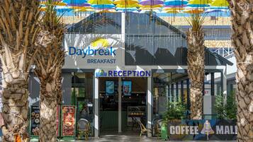 Restaurante Desayuno al Amanecer con zona de recepción, asientos al aire libre y una llamativa exhibición de sombrillas.