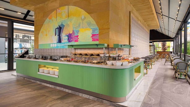 A buffet area with a green counter, glassware, and a colorful mural above. - Days Inn By Wyndham Alanya (Alanya)