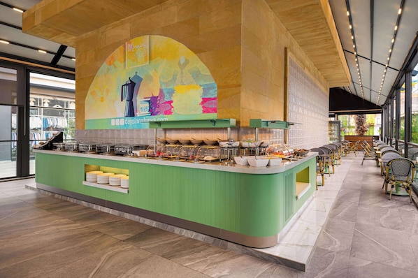 A buffet area with a green counter, glassware, and a colorful mural above. - Days Inn By Wyndham Alanya (Alanya)