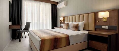 A modern hotel room with a large bed, a desk, and a chair.