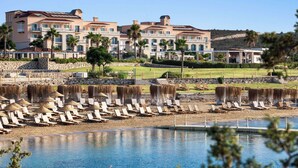 A resort with a pool, sun loungers, and a large building with multiple balconies.