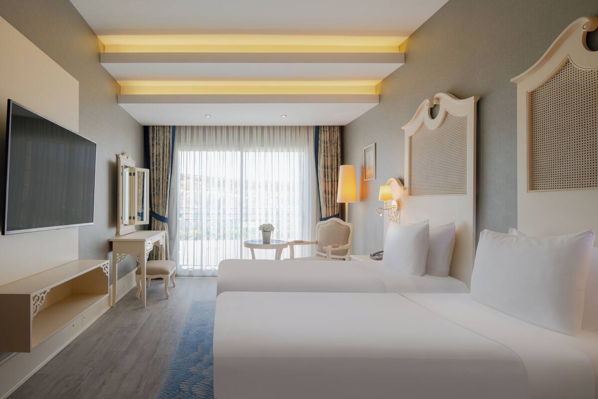 Ein Hotelzimmer mit einem großen Bett, einem Fernseher, einem Schreibtisch und einem Stuhl.