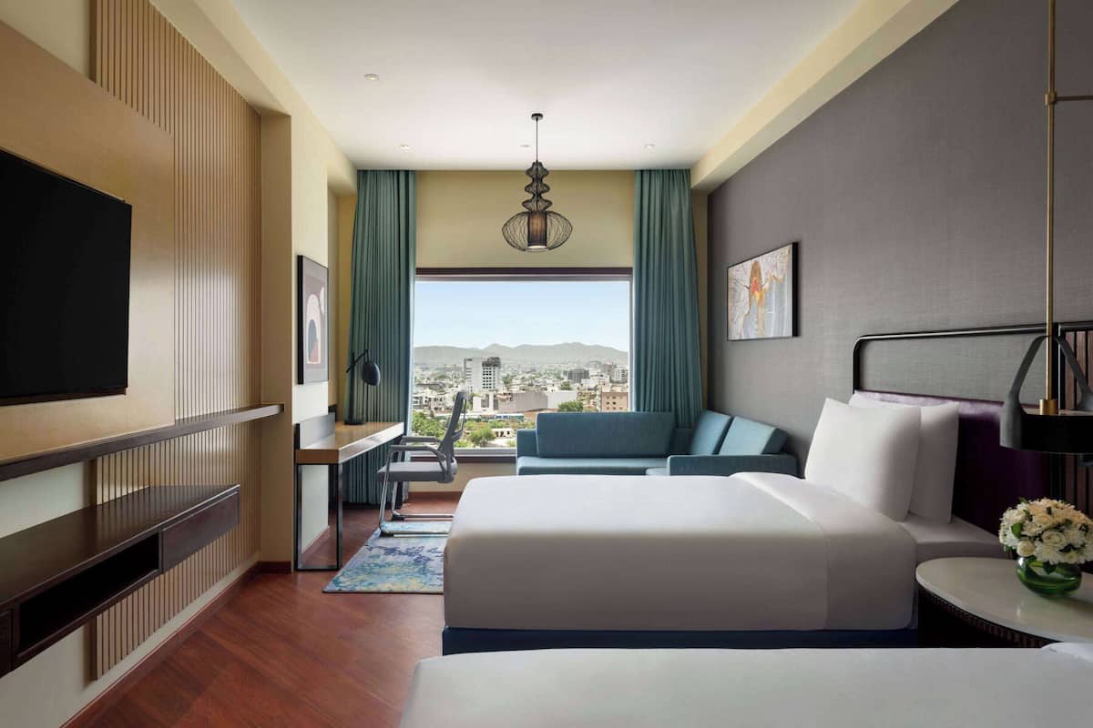 Een moderne hotelkamer met een groot bed, een bureau, een stoel en uitzicht op de stad.