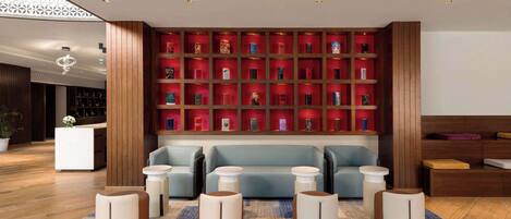 A modern lobby with a blue sofa, white round tables, and a red bookcase.