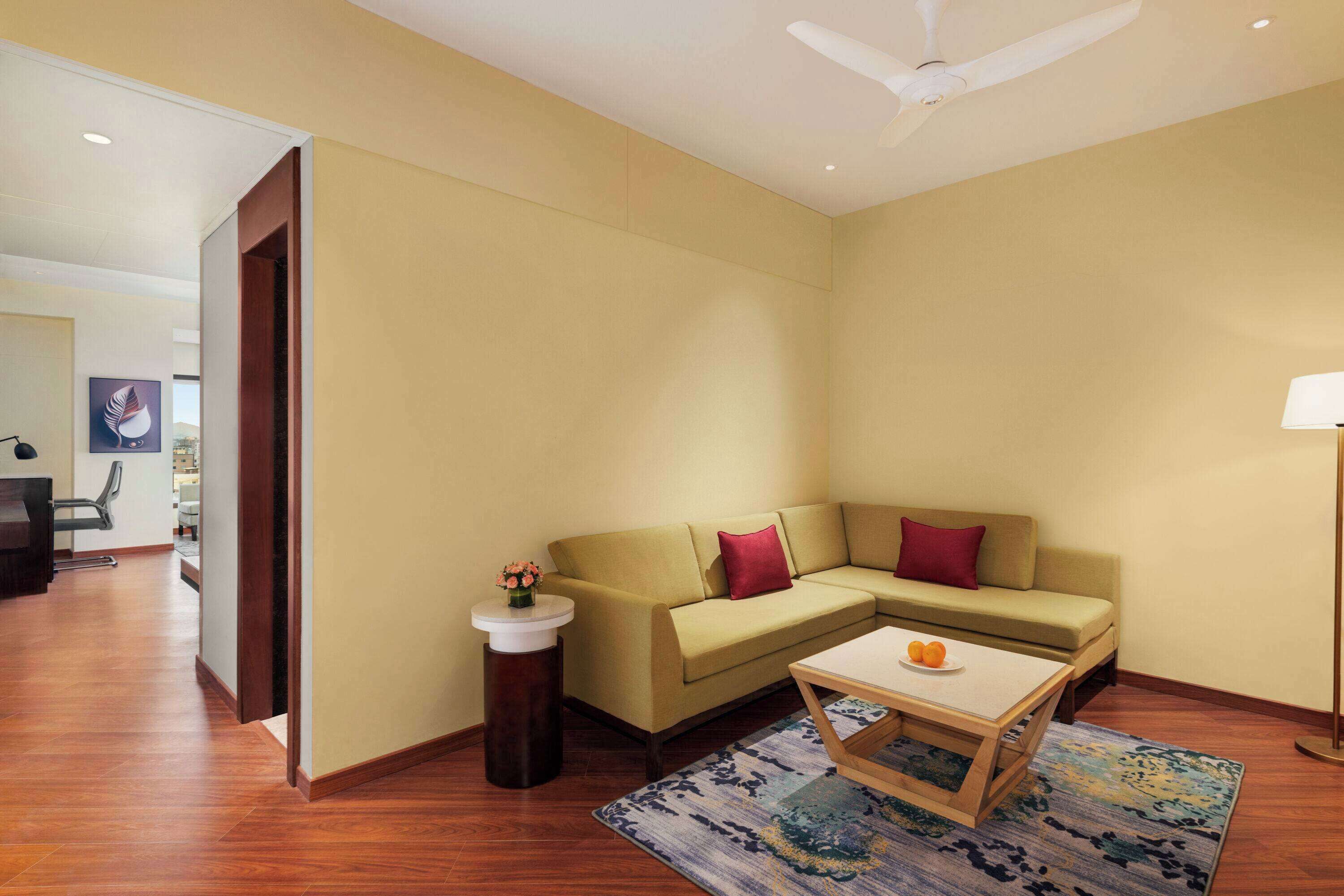 A modern living room with a beige sofa, a small coffee table, and a patterned rug.