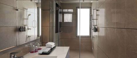 A modern bathroom with a glass-enclosed shower, a large mirror, and a white sink.