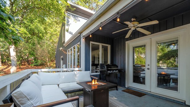 Eine überdachte Terrasse im Freien mit Feuerstelle, Sitzgelegenheit und Grill.