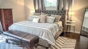 Ein Schlafzimmer mit einem großen Bett, einer Holzkombination und einem Spiegel.