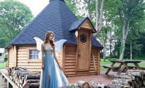 A log cabin with a steeply pitched roof, a wooden door, and a small window.