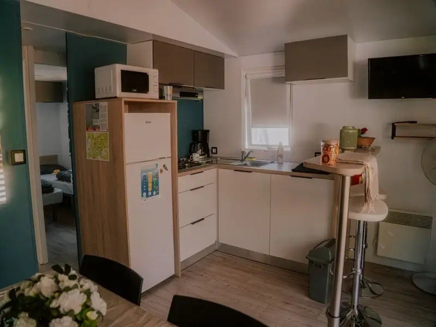 Une cuisine compacte équipée d’un four à micro-ondes, d’un réfrigérateur, d’un évier et d’un petit coin repas avec une table et des chaises.