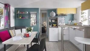 Un espace de vie compact comprenant un coin repas, une kitchenette et une petite salle de bain.