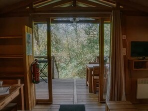 A wooden interior with a view of a forest through a glass door.