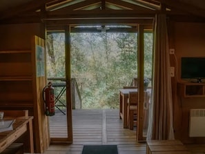 Een houten interieur met uitzicht op een bos door een glazen deur.