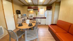 Een kleine keuken met een eettafel, stoelen, een bank en basisvoorzieningen.