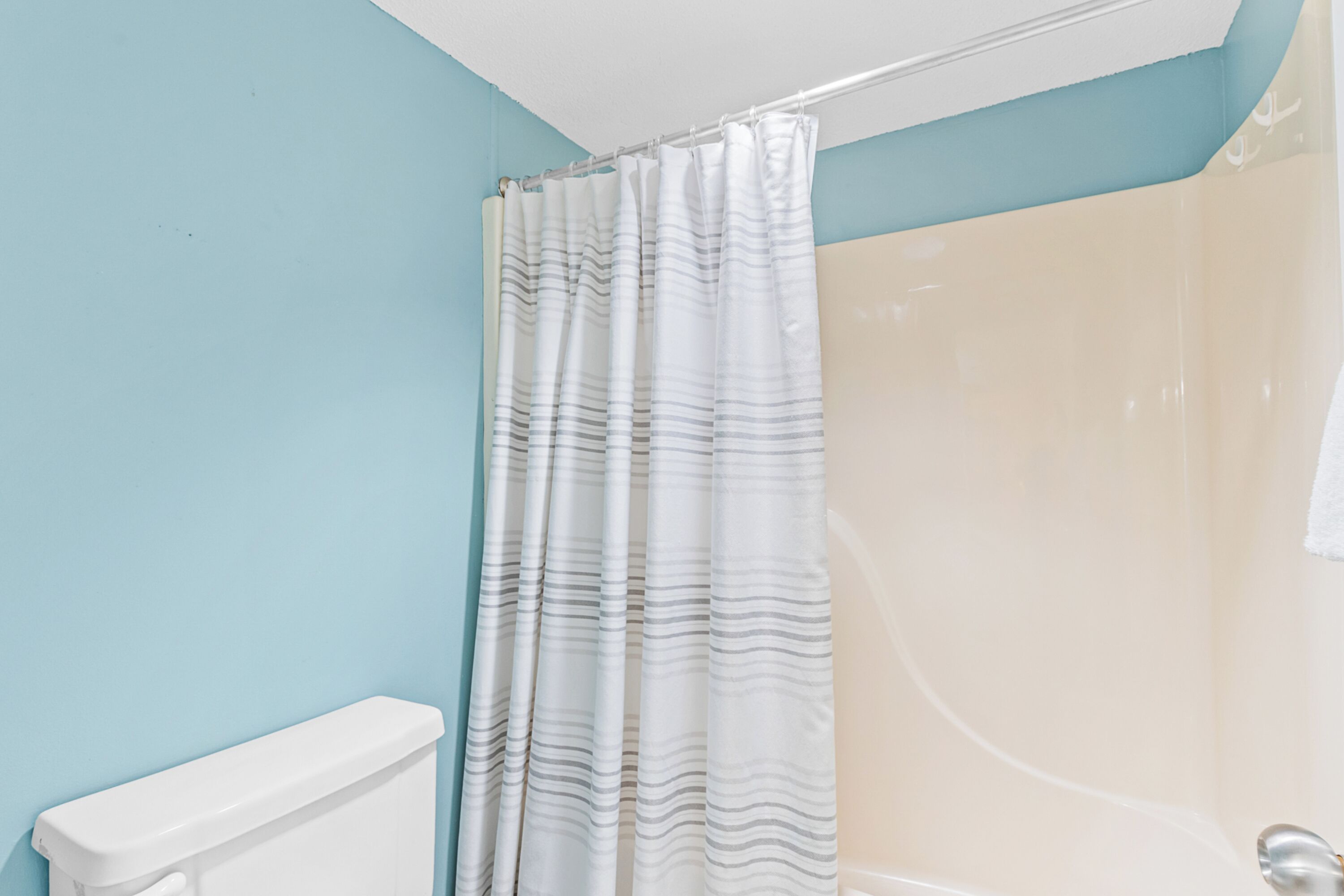 A bathroom with a shower curtain, a toilet, and a bathtub.