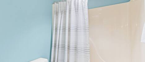 A bathroom with a shower curtain, a toilet, and a bathtub.