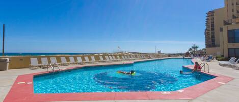 A swimming pool with a red border, a lifeguard chair, and a view of the ocean.