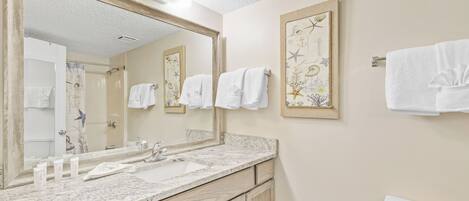 A bathroom with a large mirror, two sinks, wooden cabinets, and a toilet.