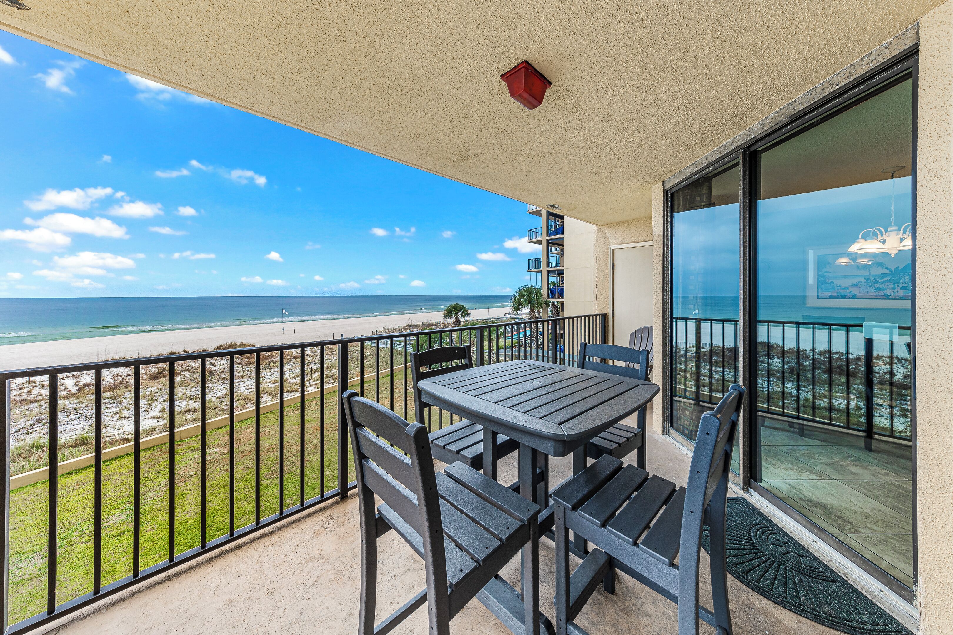 A balcony with a table and chairs overlooking a beach.