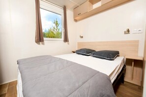 A bedroom with a bed, a window, a headboard, and a built-in shelf.
