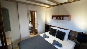 Ein Schlafzimmer mit einem großen Bett, einem Holz-Kopfteil und einem kleinen Regal mit einer Pflanze.