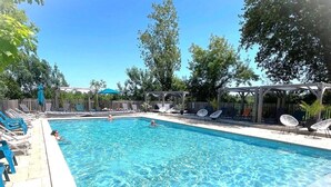 Ein rechteckiger Pool mit klarem, blauem Wasser, umgeben von Liegestühlen und Sonnenschirmen.