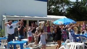 An outdoor gathering with people dancing and a blue umbrella.