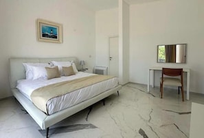 A bedroom with a bed, a desk, and a chair.
