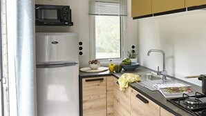 A modern kitchen with a refrigerator, microwave, sink, and stove.